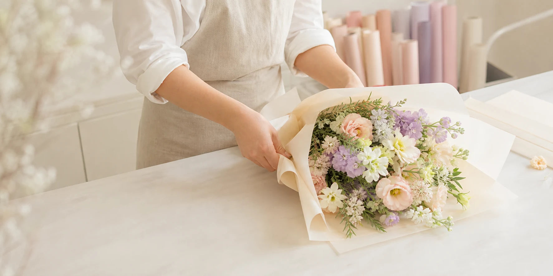 Florist hands wrapping a daily bouquet with paper rolls bags and ribbon