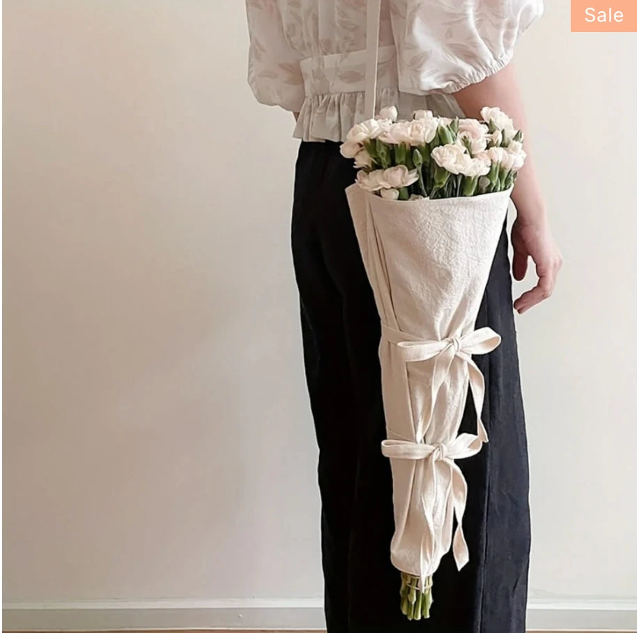 Cream wrapped bouquet held by florist in a clean editorial setting