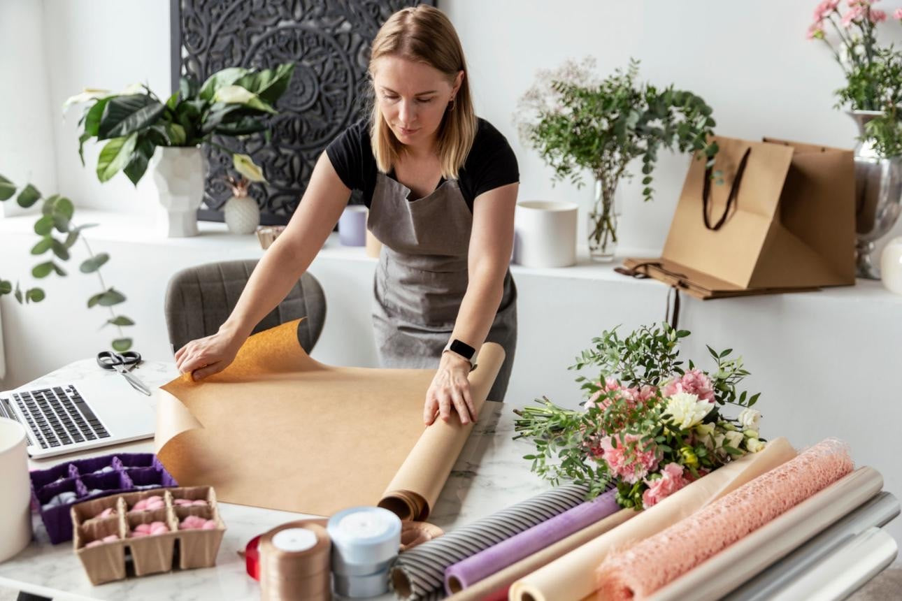 Professional florist preparing flower wrapping paper in a bright studio